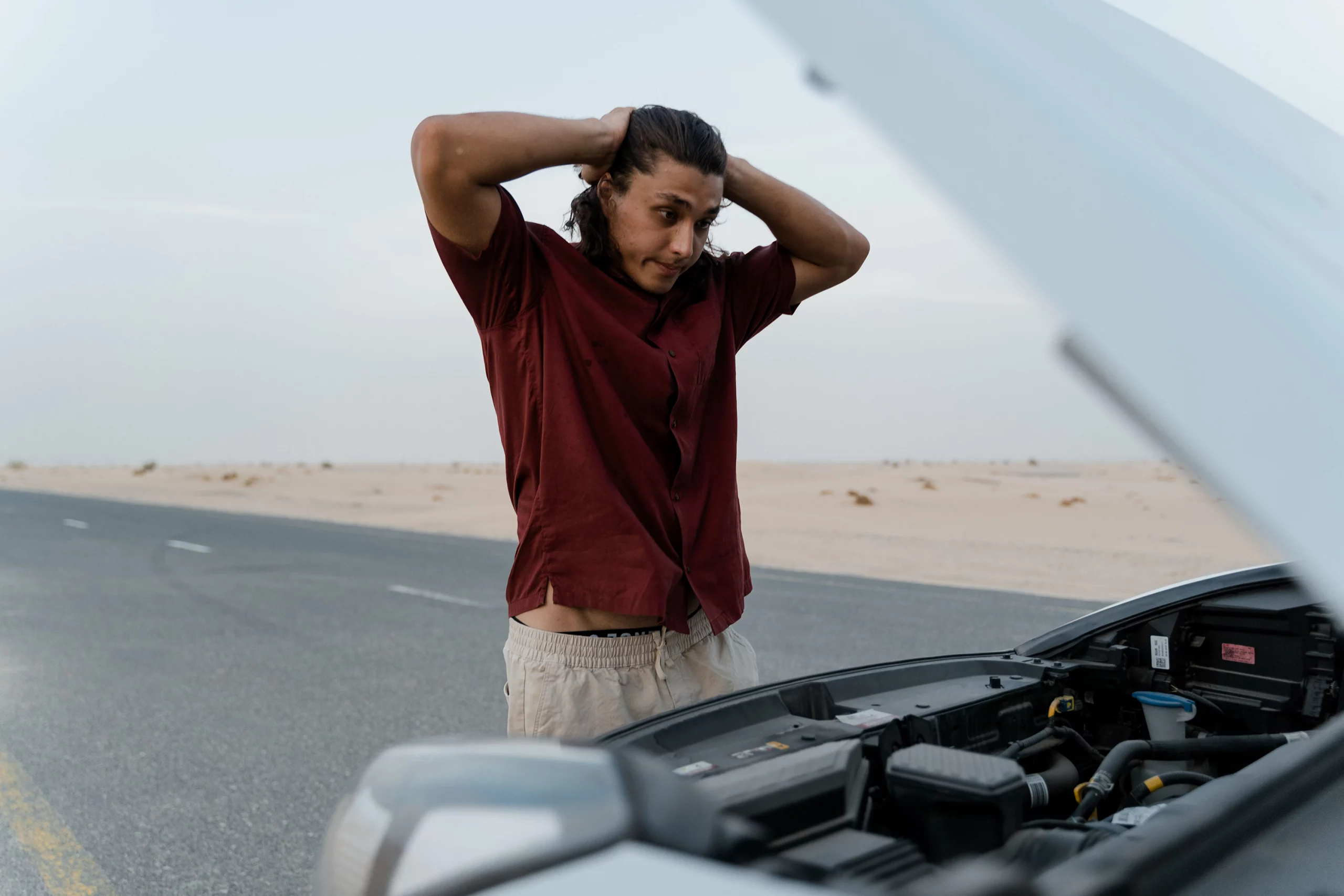 Driver looking at a vehicle with a dead battery