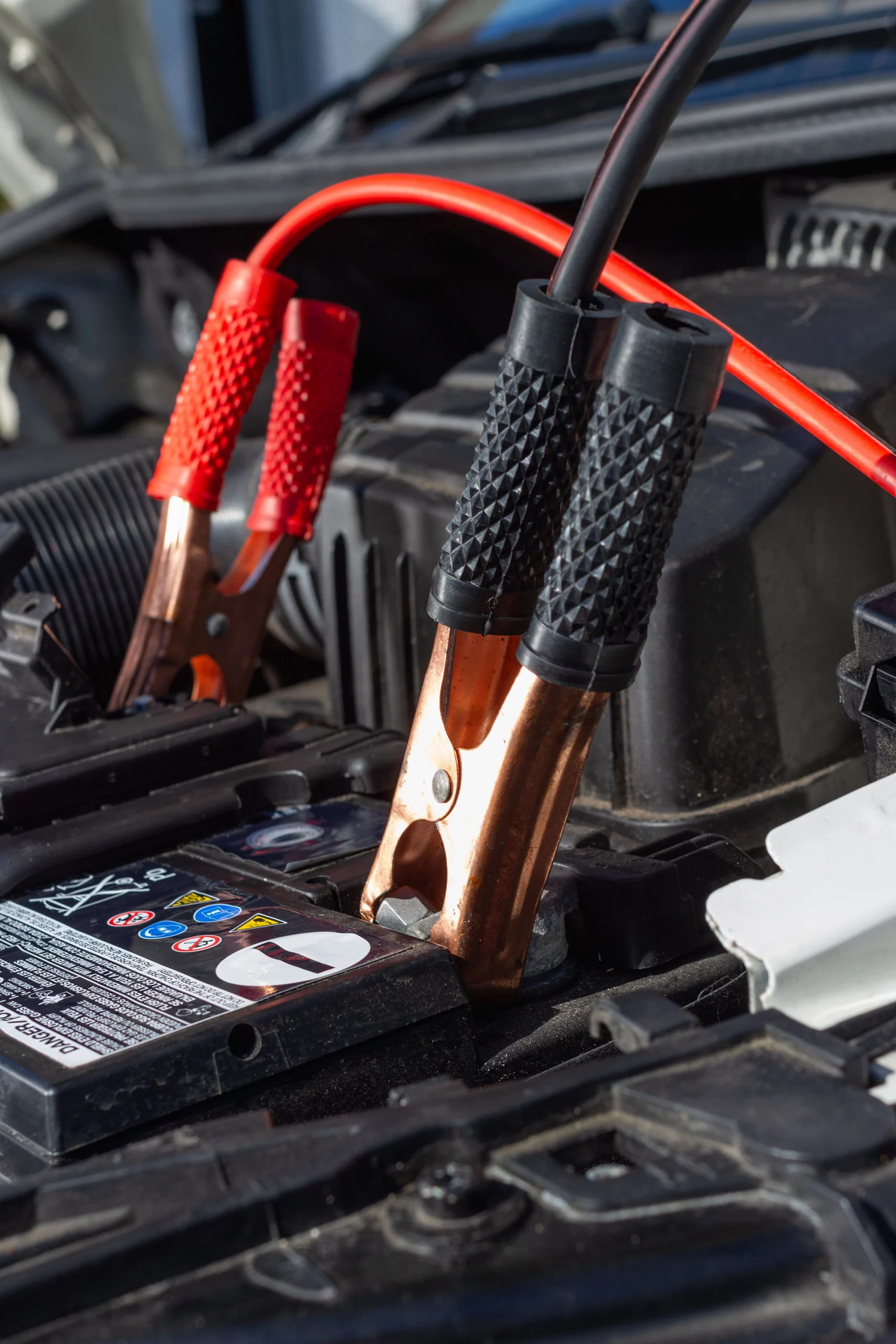 Close-up of a car battery being charged with clamps attached