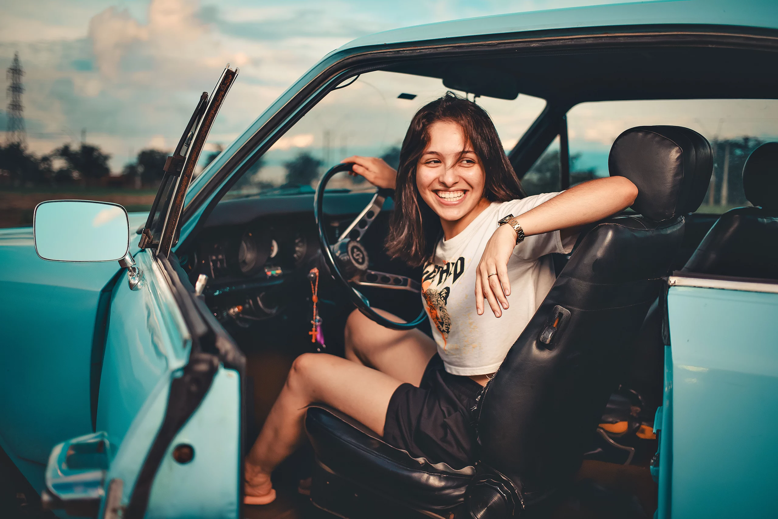 Woman smiling in a vintage convertible car ready for a road trip