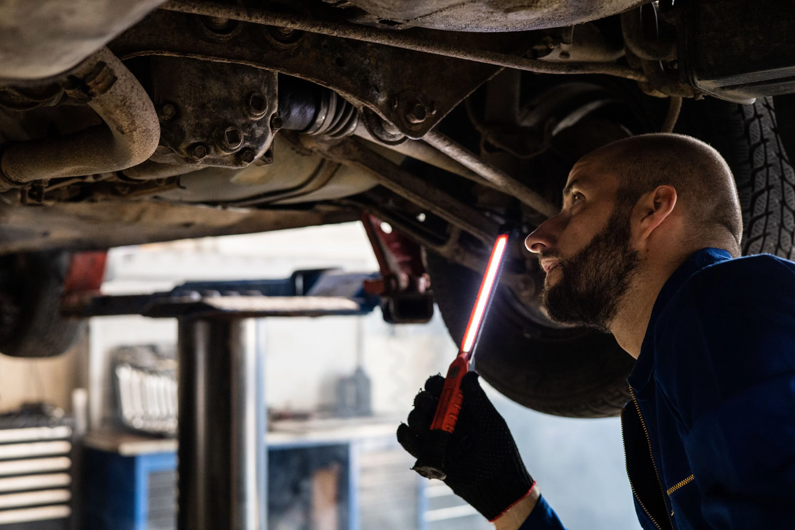 Technician inspecting a vehicle's undercarriage