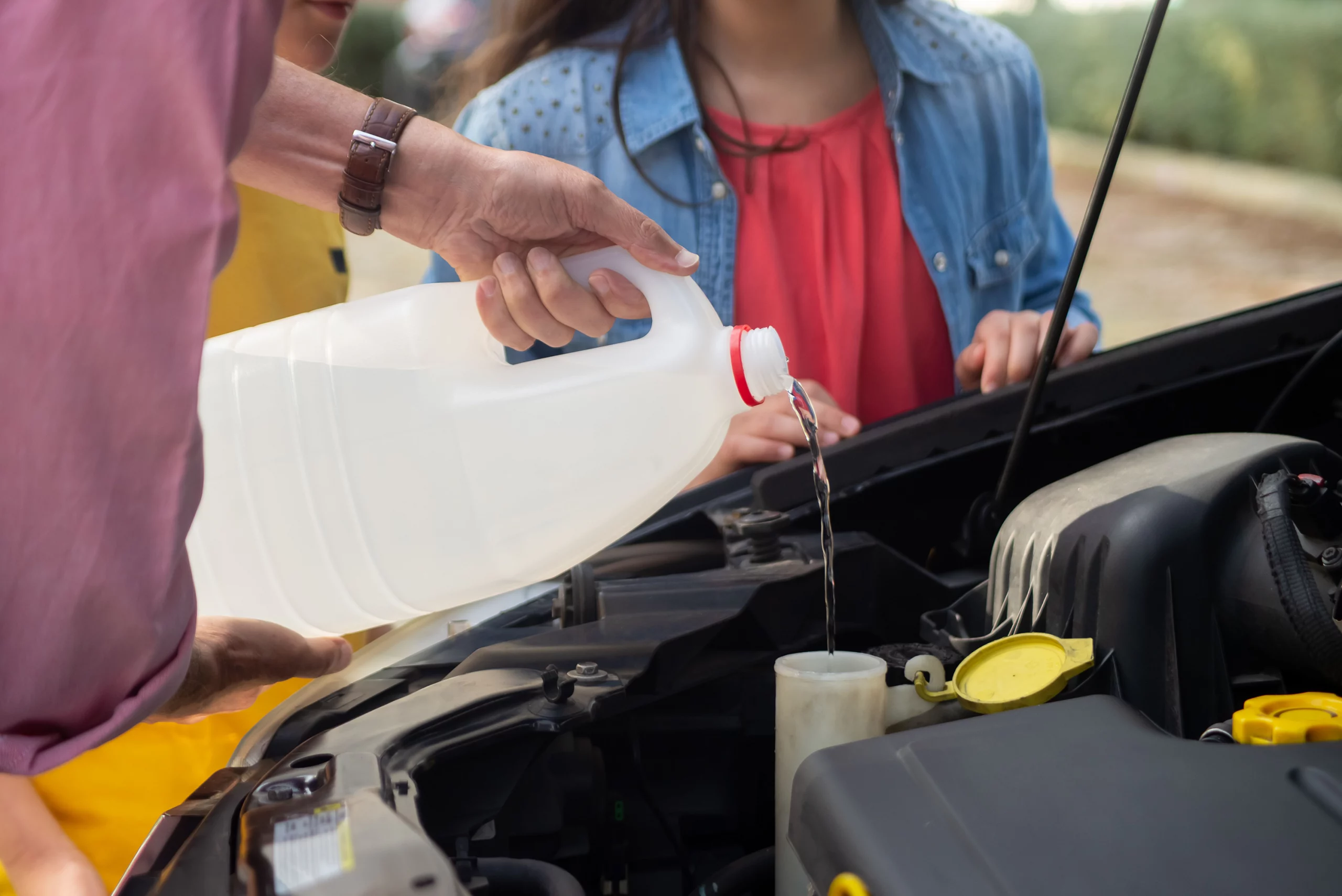 Technician pouring windshield washer fluid into a container in a car