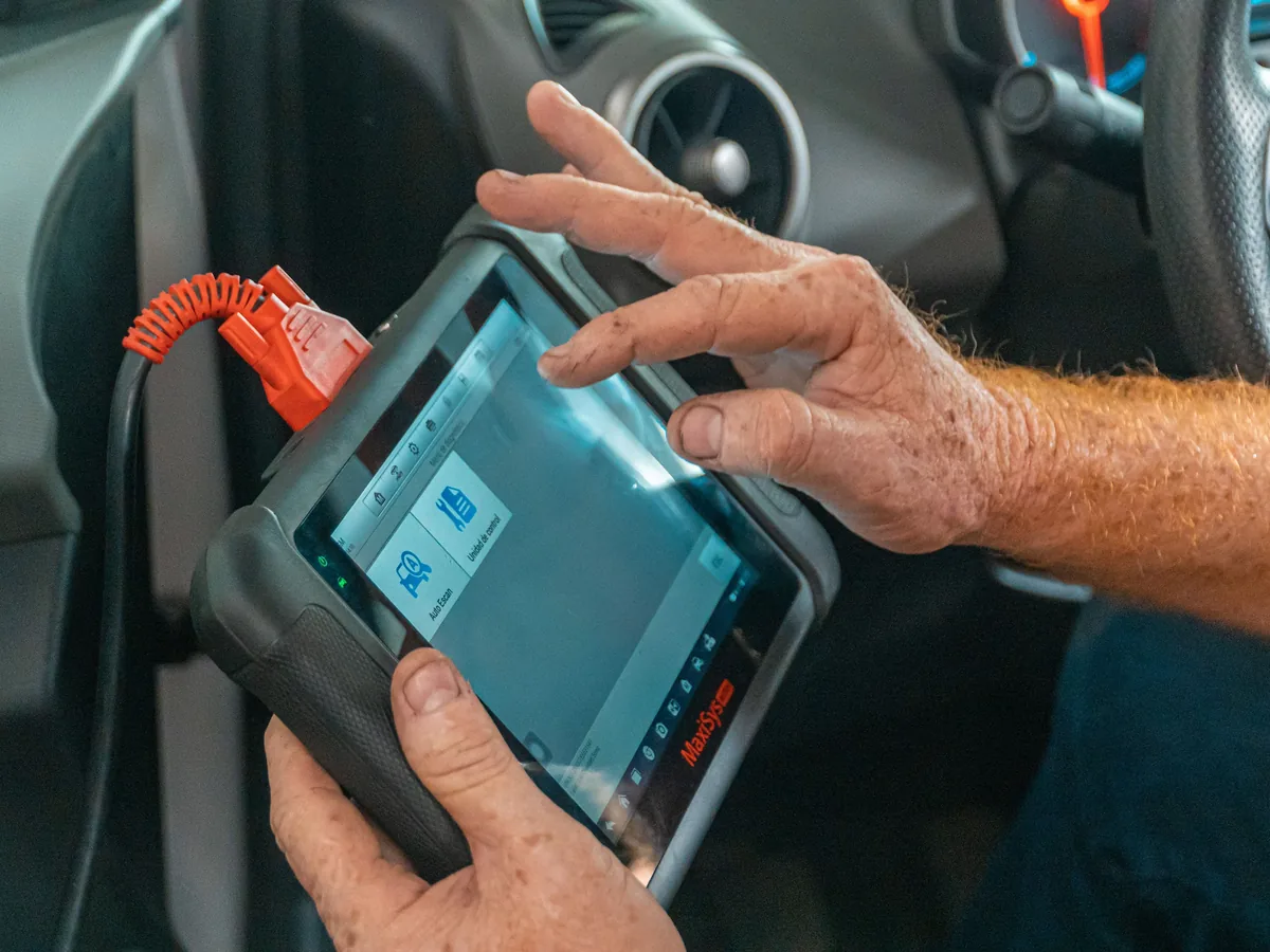 Technician using a diagnostic scan tool plugged into a car