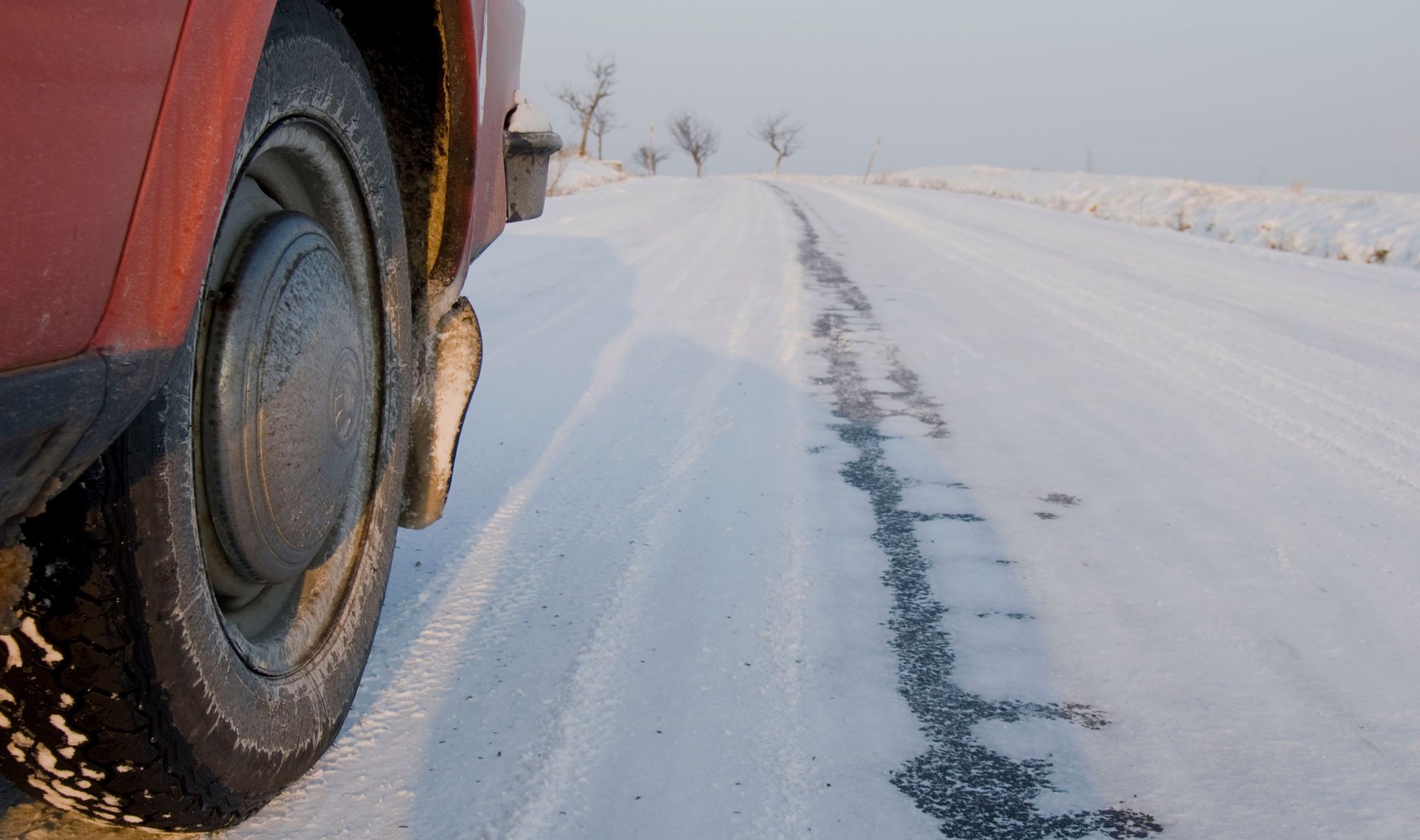 Slush and snow on the wheel and lower body of a car on a winter road