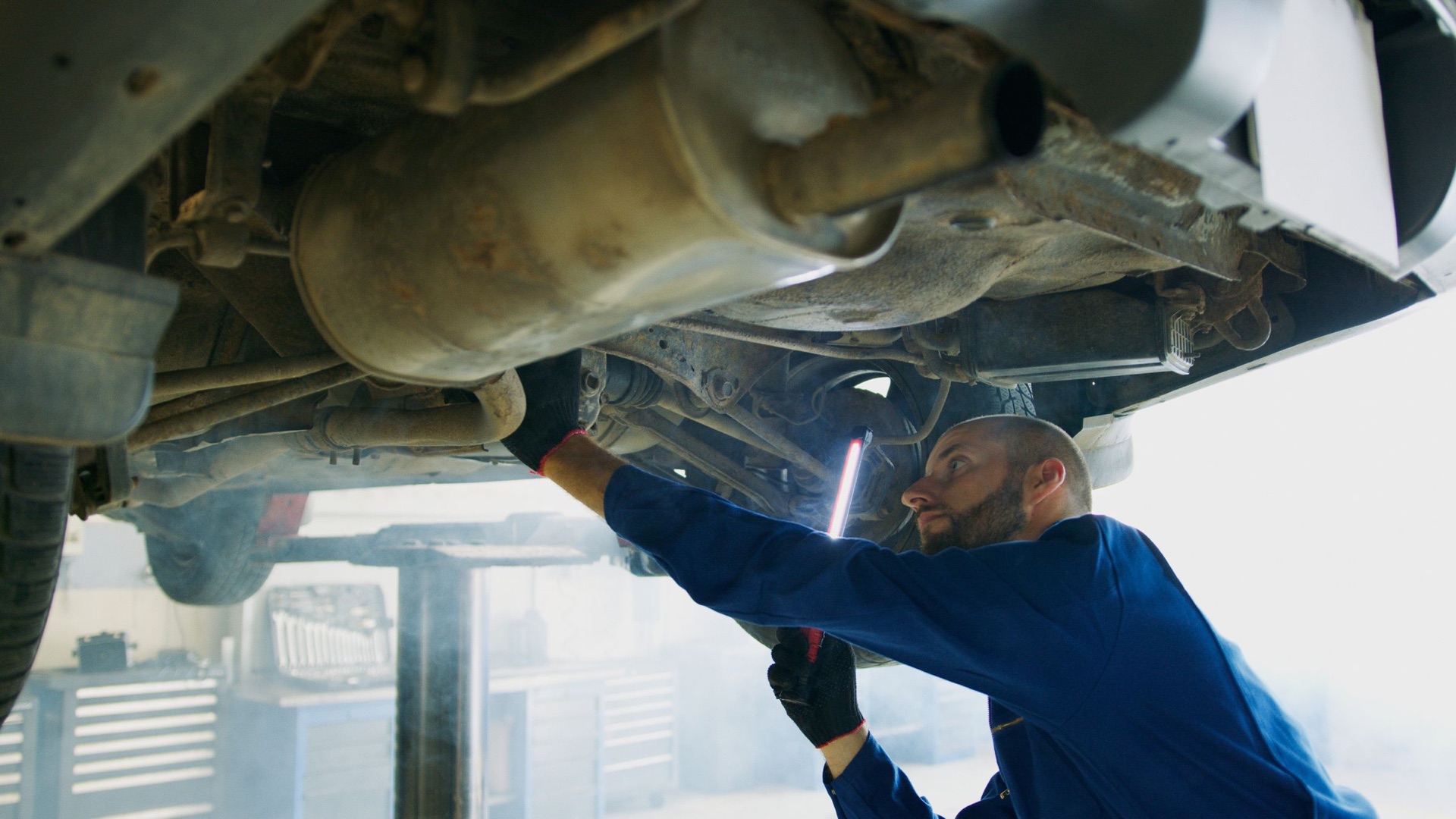 Mechanic inspecting a vehicle's muffler and exhaust pipe on a lift