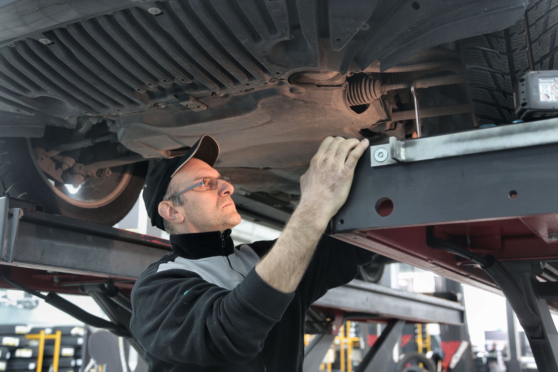 Technician inspecting underbody corrosion protection on a vehicle